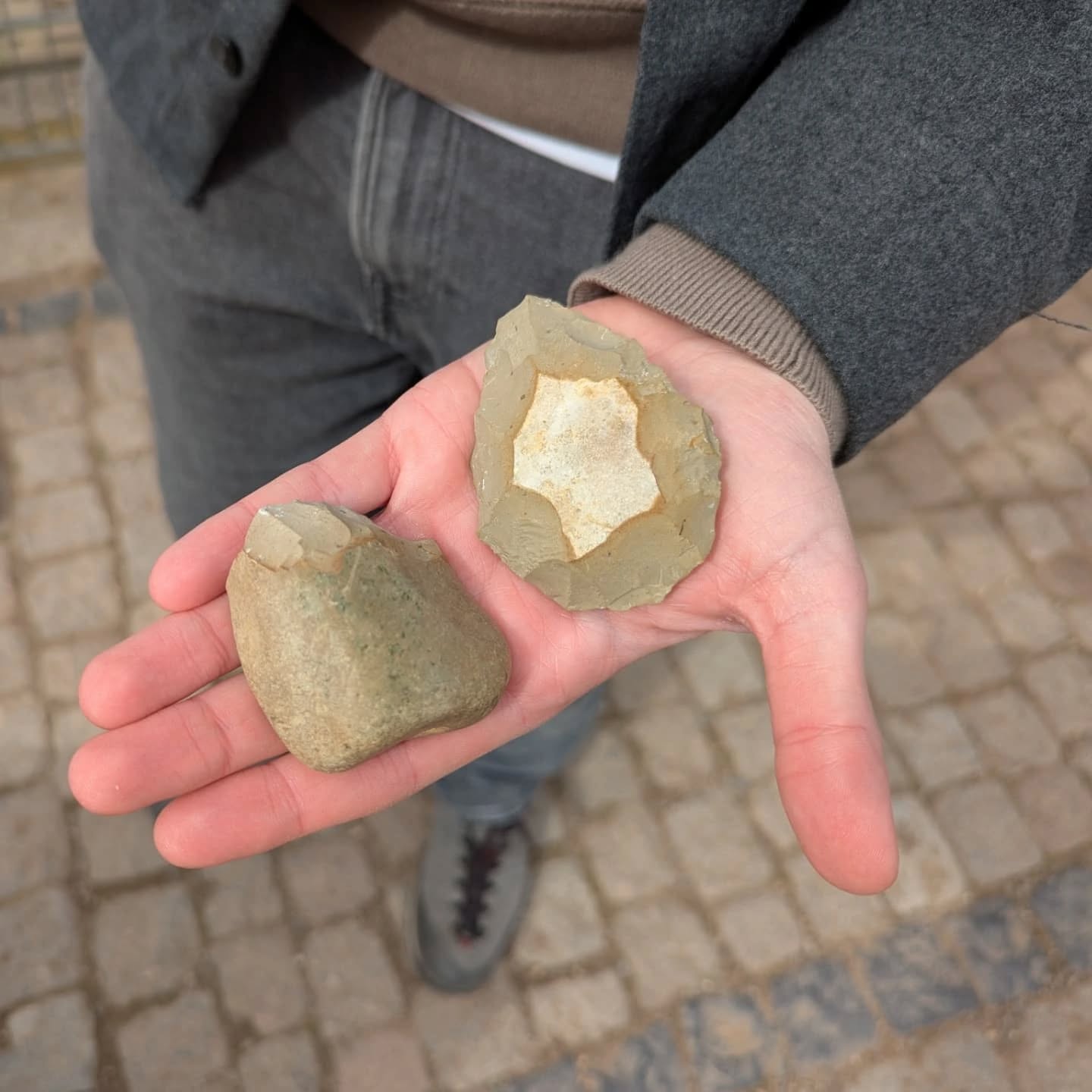 Eine Hand hält zwei Steine. Die Steine sehen alt und abgenutzt aus.