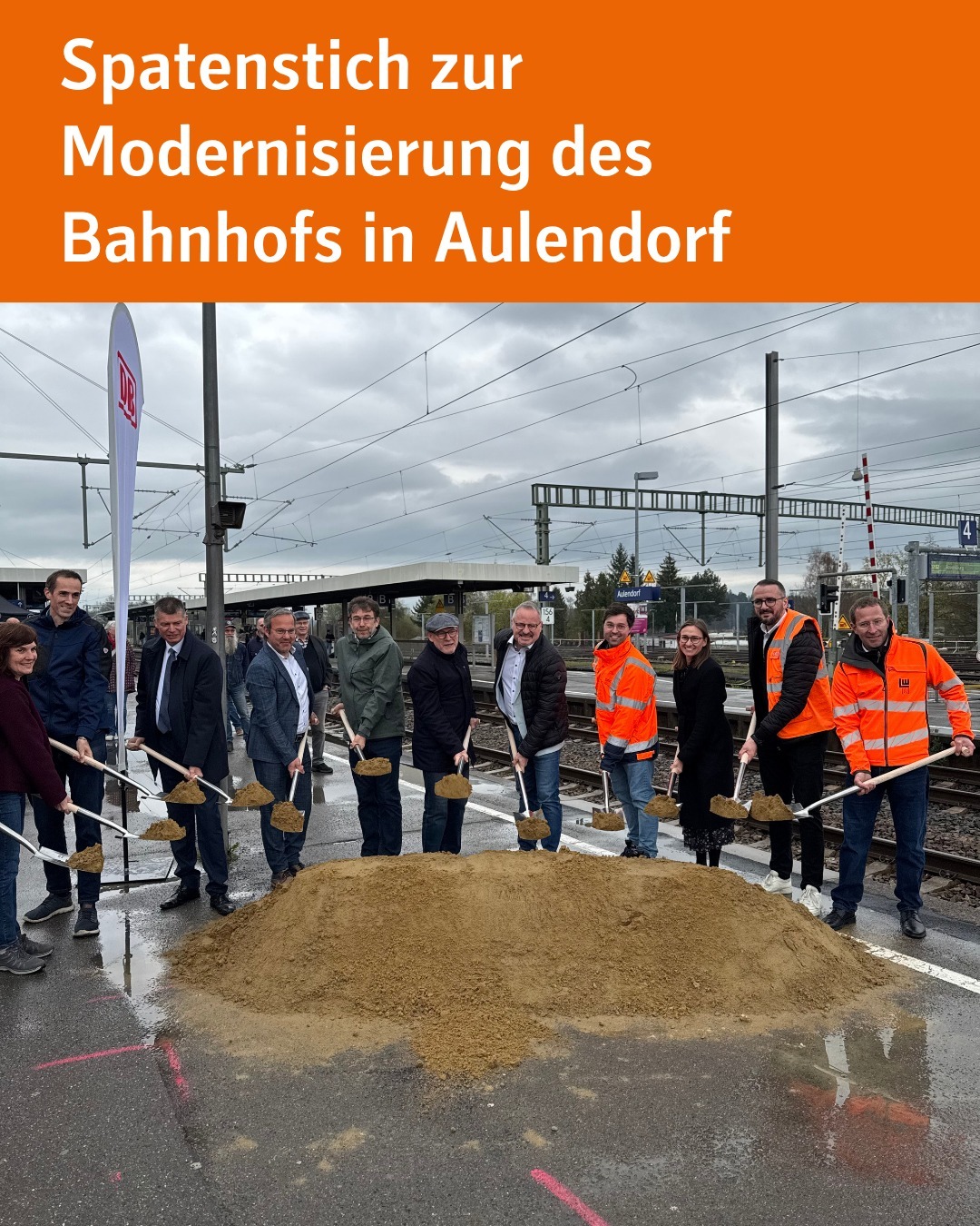 Zu sehen sind mehrere Personen, die vor einem Erdhaufen stehen. Alle Personen halten Spaten mit Erde in der Hand. Unter den Personen befinet sich Michale Groh, Leiter des Regionalbereichs Südwest von der DB InfraGO AG, Verkehrsminister Winfried Hermann, Bürgermeister der Gemeinde Aulendorf Matthoas Burth und unsere stellvertretende Landrätin Anna Maria Ostermeier. Bildtext: Spatenstich zur Modernisierung des Bahnhofs in Aulendorf.