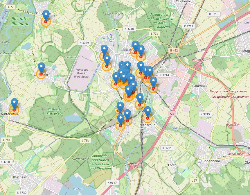 Dieser Alternativtext wurde KI-generiert: Eine Karte zeigt ein Gebiet mit Straßen, grünen Flächen und vielen blauen Markierungen. Verschiedene Ortsnamen und Straßennamen sind auf der Karte zu sehen.
