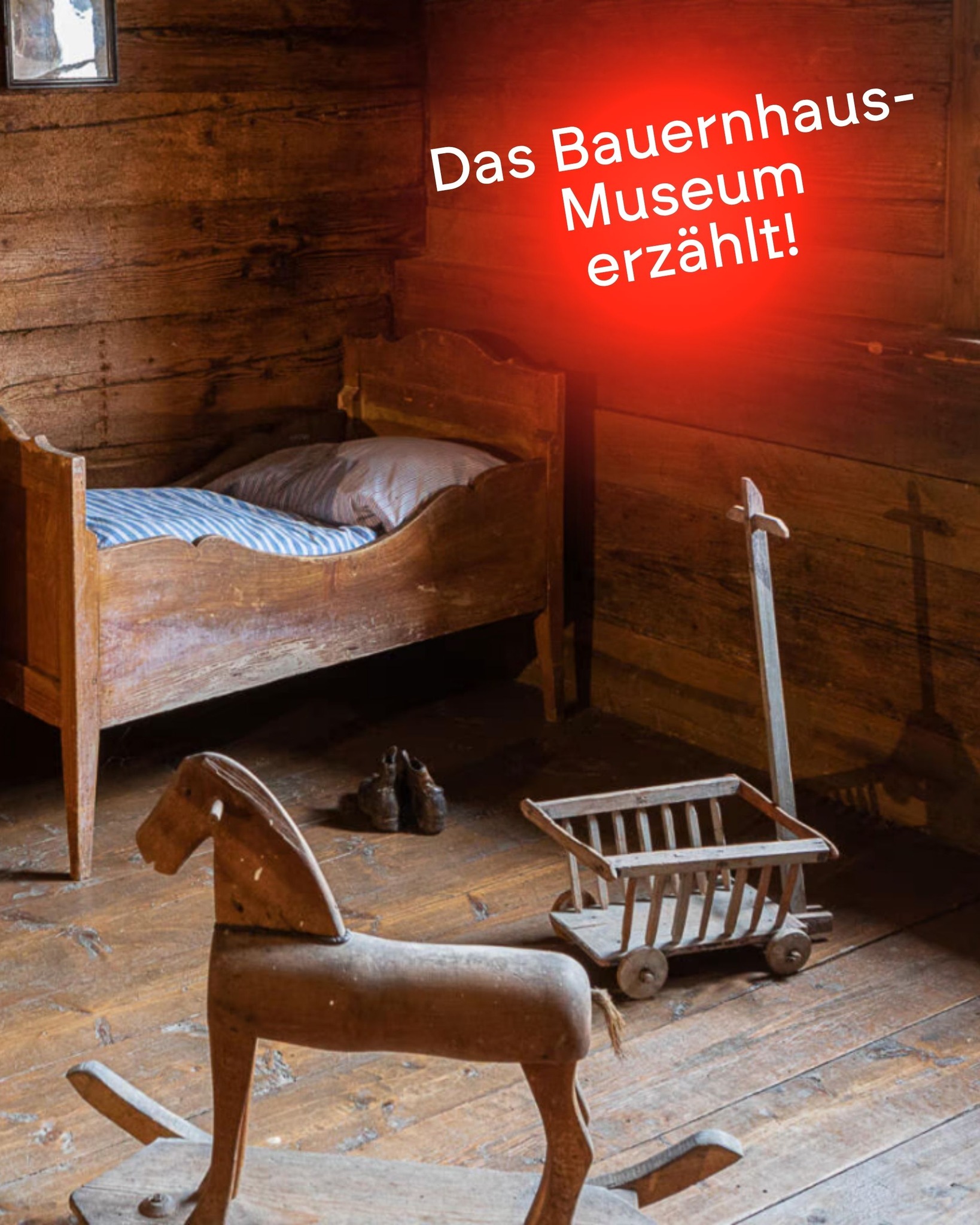 Dieser Alternativtext wurde KI-generiert: Ein Innenraum mit Holzboden und mehreren Gegenständen, darunter ein Bett, ein Schaukelpferd und Körbe. Der Raum wirkt historisch und ist warm beleuchtet.