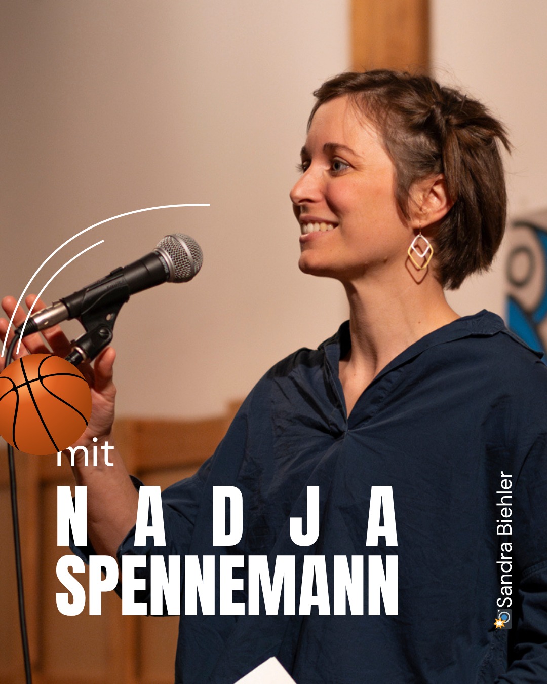 Eine Person mit kurzen Haaren und Kopfbedeckung hält ein Mikrofon und lächelt, daneben ein Basketball und der Text „mit NADJA SPENNEMANN“. Rechts unten steht „©Sandra Biehler“. (KI-Alternativtext)