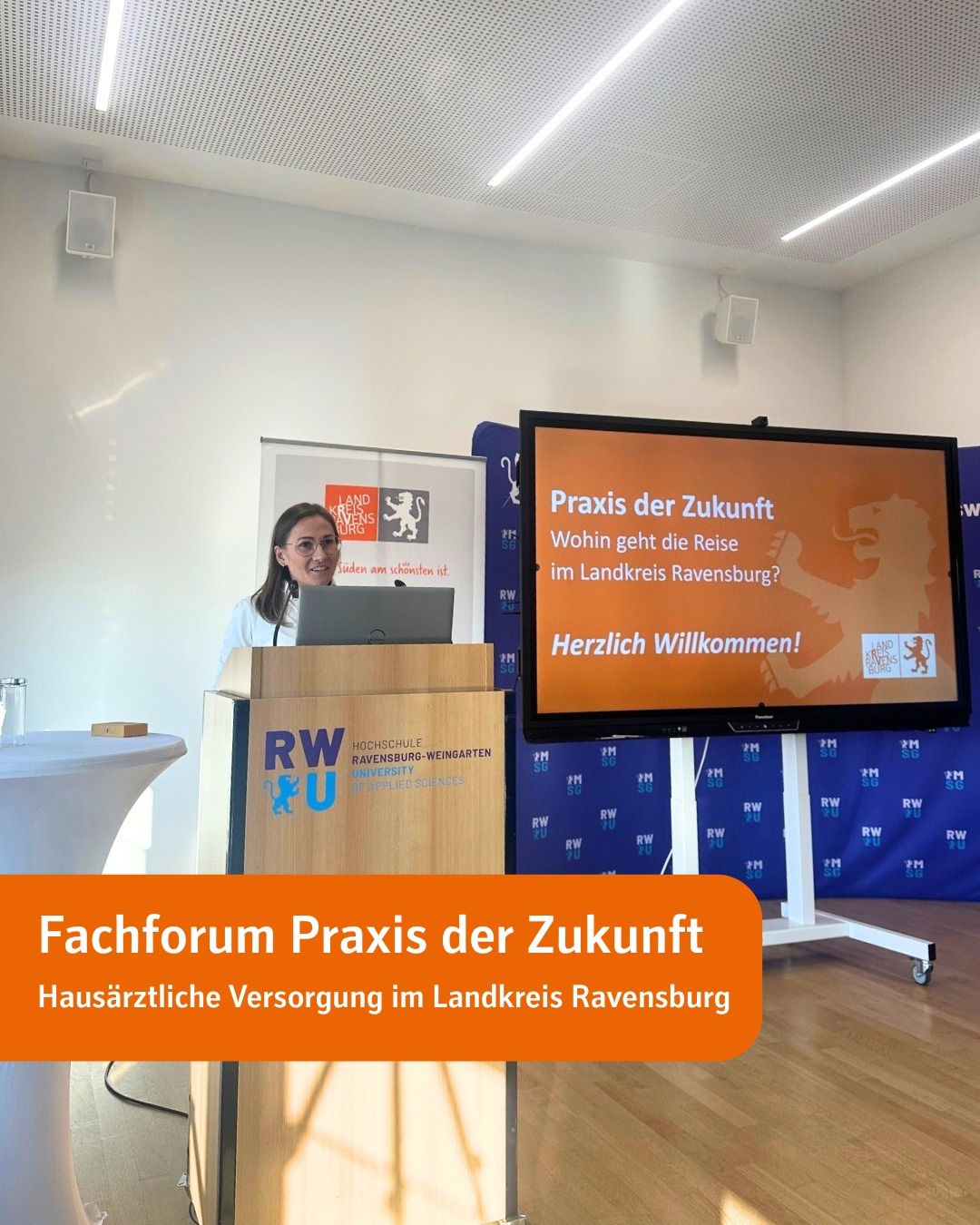 Eine Frau (Anna Maria Ostermeier) steht an einem Rednerpult in einem Saal und blickt ins Publikum. Text im Bild: Fachforum Praxis der Zukunft. Hausärztliche Versorgung im Landkreis Ravensburg