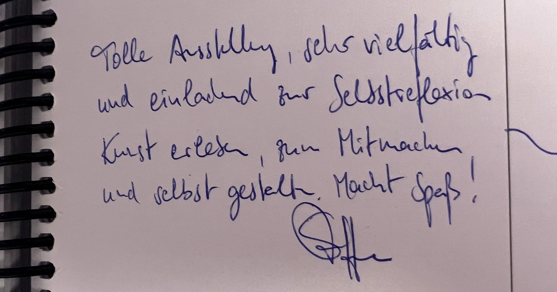 Dieser Alternativtext wurde KI-generiert: Schwarz-weißes Foto einer beschriebenen Seite in einem Spiralblock. Deutlich erkennbare Handschrift mit Text und einer Unterschrift am unteren Rand.