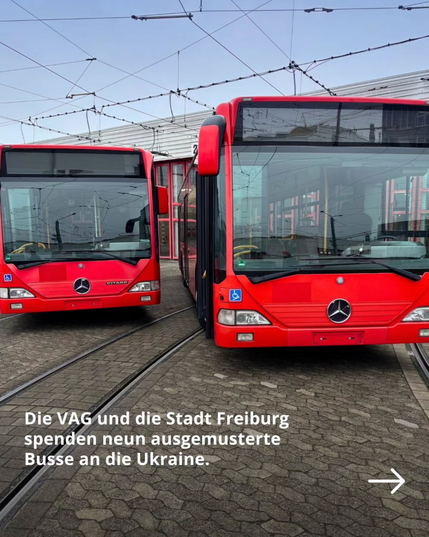 Dieser Alternativtext wurde KI-generiert: Mehrere rote Busse stehen nebeneinander auf Gleisen. Im Hintergrund sind Gebäude und Stromleitungen zu sehen.