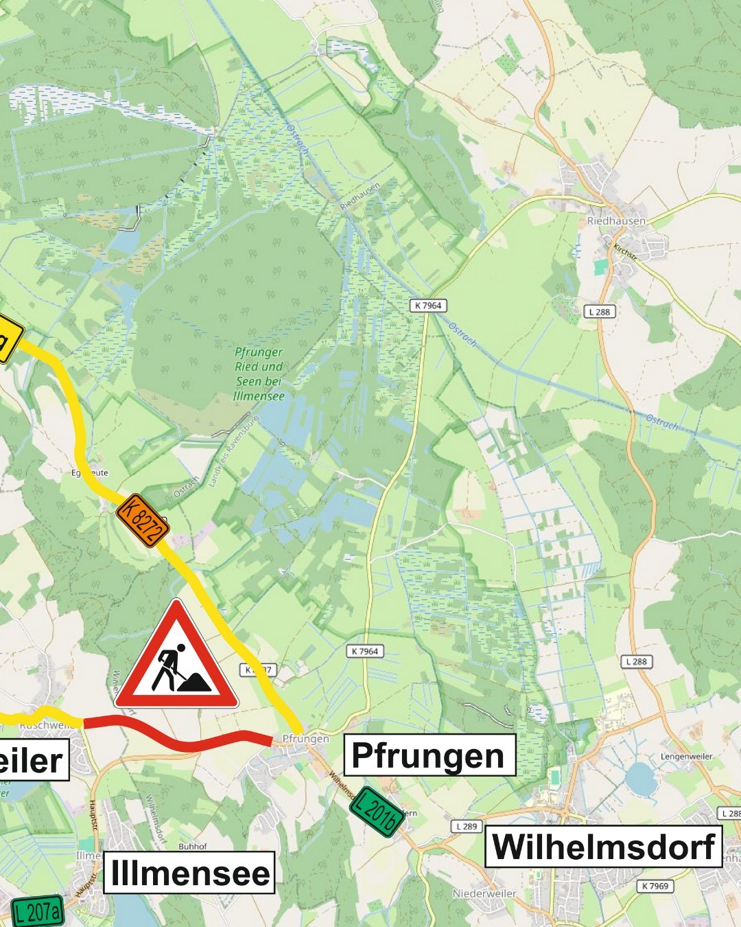 Eine farbige Karte zeigt ein ländliches Gebiet mit Straßen, Feldern und Gewässern. Ein Warnschild für Fußgänger ist auf der Karte zu sehen.