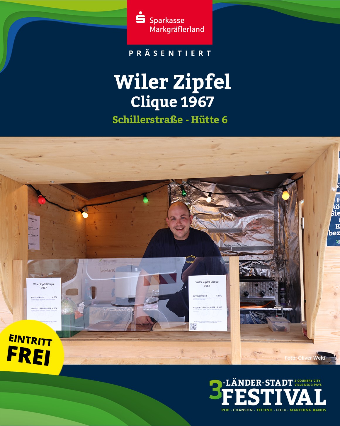 Eine Person steht in einem Imbissstand mit Speisekarte, der durch eine Sparkasse präsentiert wird. Im unteren Bildbereich ist ein Logo der Veranstaltung zu sehen.