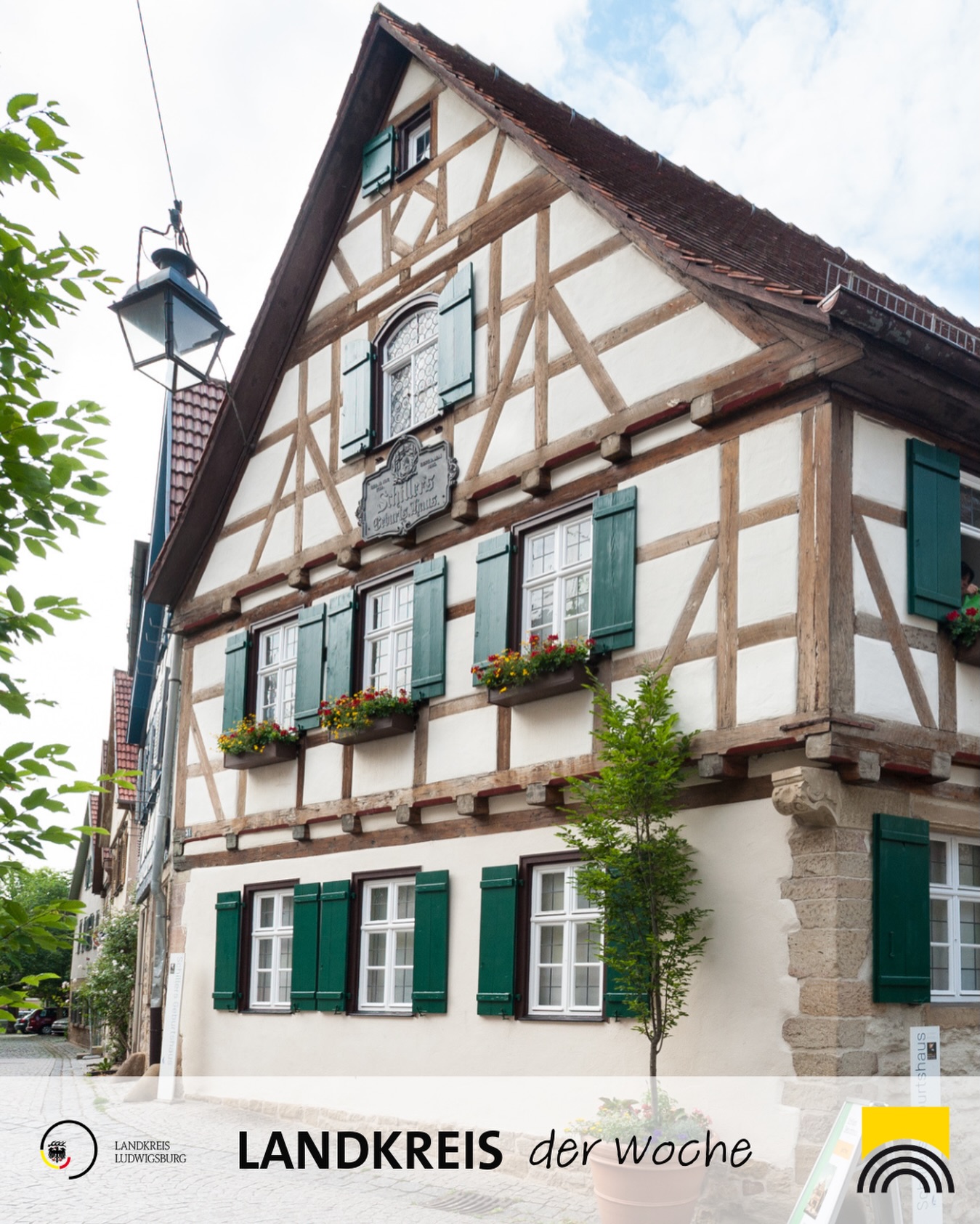 Dieser Alternativtext wurde KI-generiert: Ein traditionelles Fachwerkhaus mit grünen Fensterläden und Blumenkästen ist zu sehen. Das Bild ist farbig und zeigt ein Gebäude mit historischen Details.