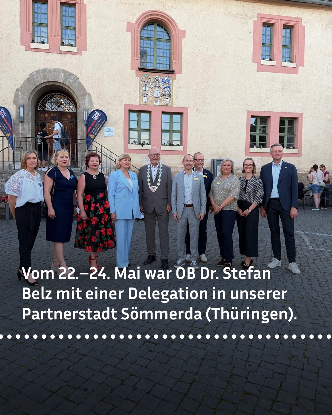 Gruppe von zehn Personen vor einem historischen Gebäude mit Wappen, darunter Text über einen Besuch von OB Dr. Stefan Belz in Sömmerda (Thüringen) vom 22. bis 24. Mai. (KI-Alternativtext)