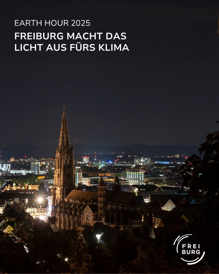 Eine nächtliche Ansicht einer Stadt mit einer beleuchteten Kathedrale im Vordergrund.  Die Lichter der Stadt sind schwach sichtbar.