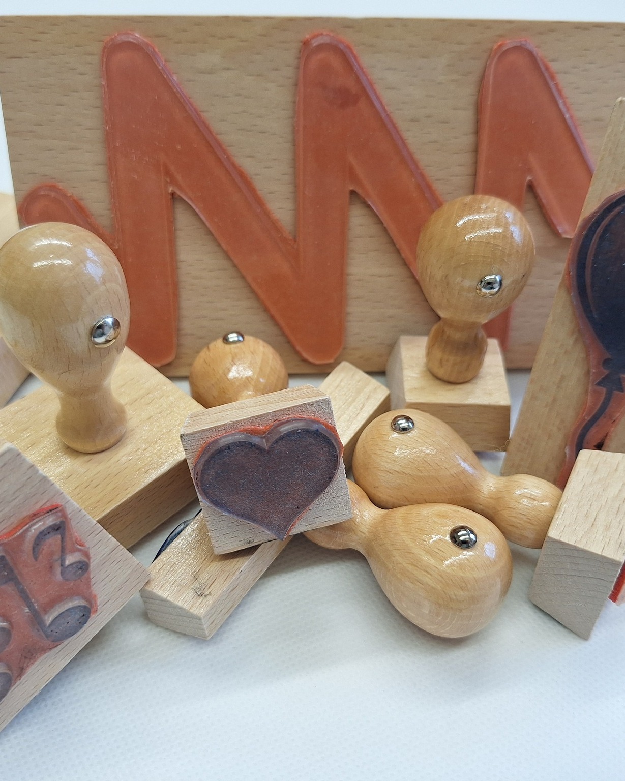 Dieser Alternativtext wurde KI-generiert: Mehrere Holzstempel und -buchstaben liegen übereinander. Darunter sind verschiedene Formen und Nummern erkennbar.