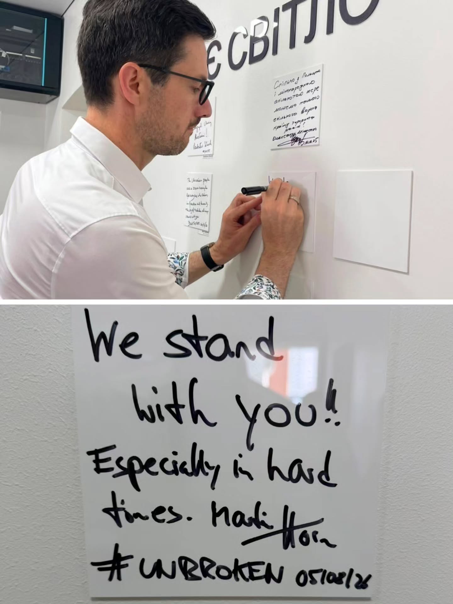 Eine Person mit Brille und weißem Hemd schreibt mit einem schwarzen Stift auf eine weiße Karte an einer Wand, neben der weitere Notizen hängen. Ein Detailbild zeigt den handschriftlichen Text auf der Karte: "We stand with you! Especially in hard times. Hadi Hor #UNBROKEN 05/02/24". (KI-Alternativtext)