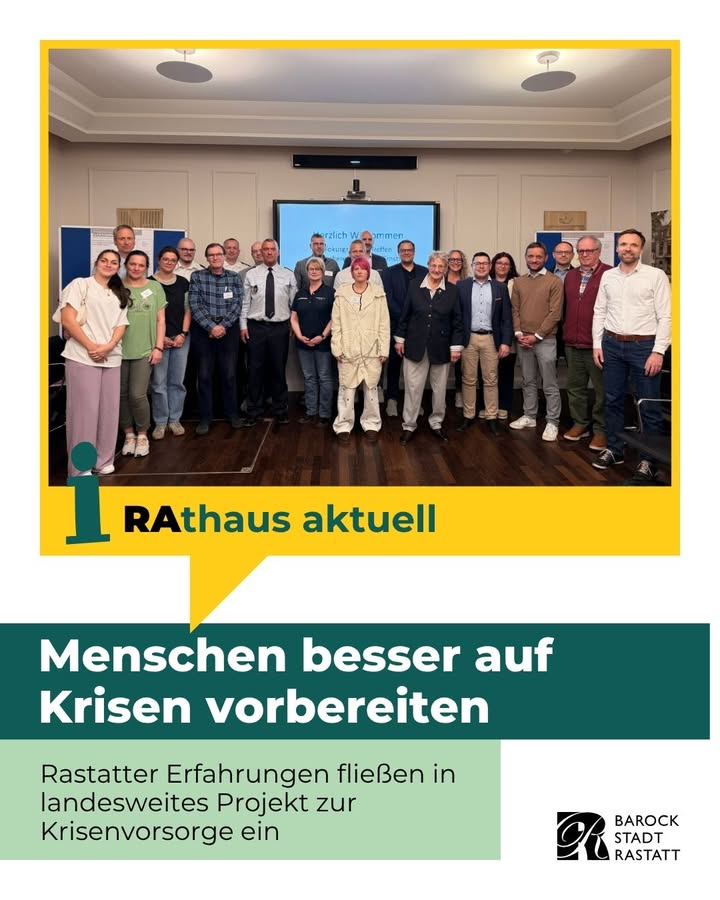 Dieser Alternativtext wurde KI-generiert: Eine Gruppe von Personen steht vor einem Gebäude mit Bannern und einem Schild mit Text. Im unteren Teil des Bildes befindet sich ein farbiger Streifen mit weiteren Informationen.