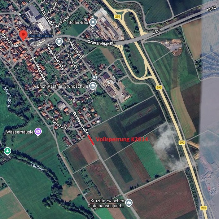 Dieser Alternativtext wurde KI-generiert: Luftaufnahme einer ländlichen Gegend mit Gebäuden, Straßen und Feldern. Eine rote Linie zeigt eine Straßensperrung an.