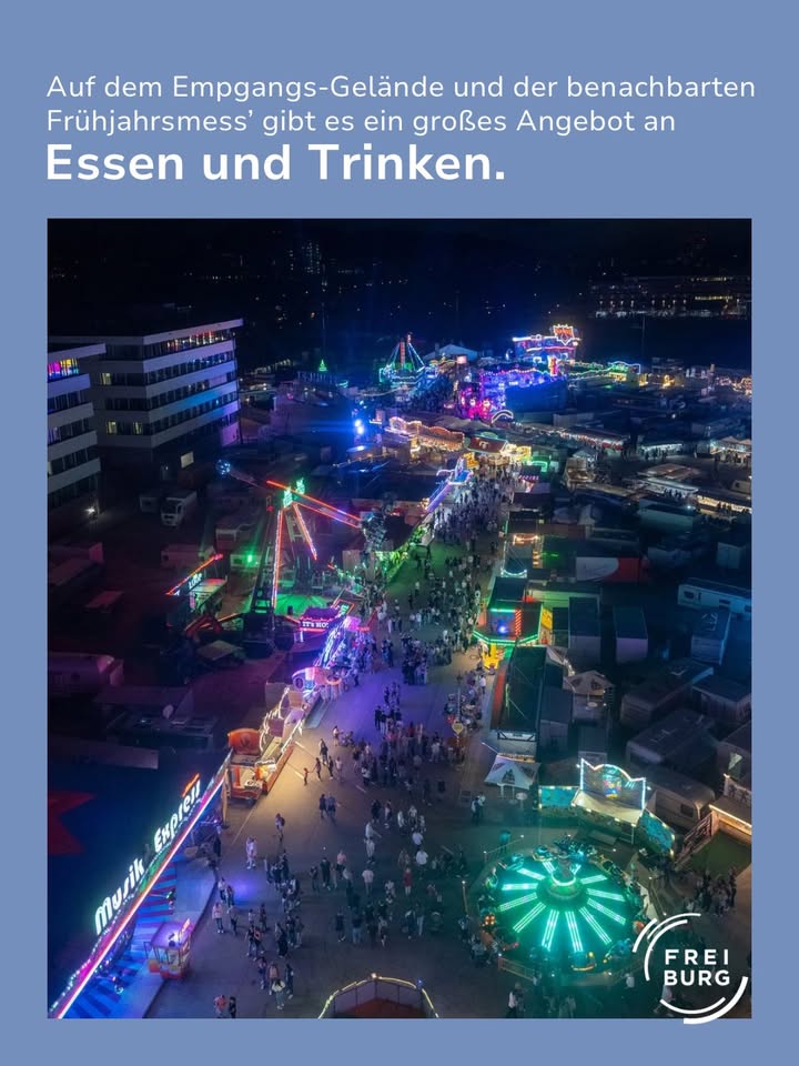 Nachtansicht eines belebten Volksfestes mit bunten Lichtern, Fahrgeschäften und Menschenmengen auf Wegen zwischen Ständen. Oben Text: „Auf dem Empgangs-Gelände und der benachbarten Frühjahrsmess’ gibt es ein großes Angebot an Essen und Trinken.“ Unten rechts Logo „FREIBURG“. (KI-Alternativtext)
