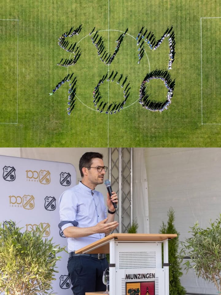 Eine Vogelperspektive zeigt Menschen auf einem Fußballfeld, die die Buchstaben SVM und die Zahl 100 bilden. Darunter hält eine Person an einem Rednerpult mit der Aufschrift Munzingen eine Rede vor einem Hintergrund mit Logos zum 100-jährigen Jubiläum. (KI-Alternativtext)