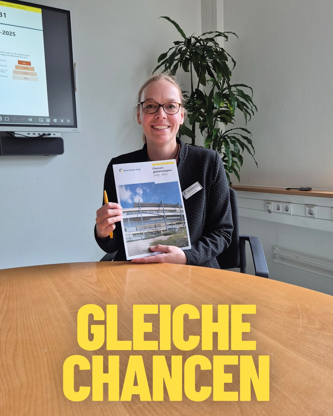Eine Person mit Brille sitzt an einem Tisch, hält ein Dokument mit dem Titel „Chancengleichheitsplan 2025–2031“ und einen Stift. Im Hintergrund ist ein Bildschirm mit Diagrammen und eine Pflanze zu sehen. Große gelbe Schrift am Tisch: „GLEICHE CHANCEN“. (KI-Alternativtext)