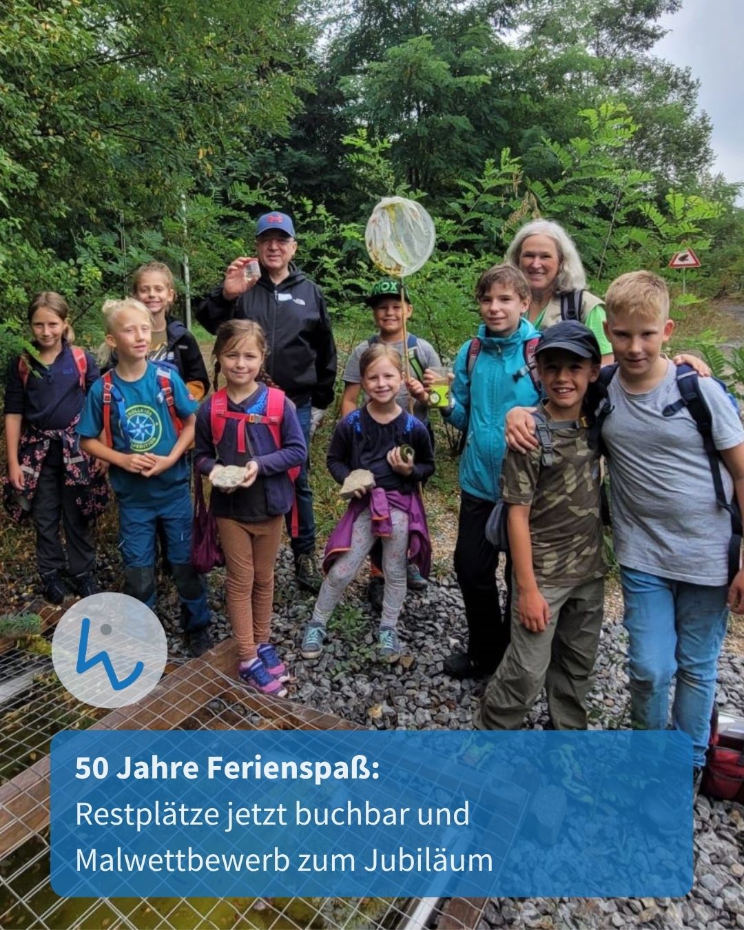 Eine Gruppe von Kindern und zwei Erwachsenen posiert im Wald, wobei einige Steine und ein Netz halten. Im Vordergrund liegt ein Gitter über Wasser. Ein blauer Textbanner unten lautet: „50 Jahre Ferienspaß: Restplätze jetzt buchbar und Malwettbewerb zum Jubiläum“. (KI-Alternativtext)
