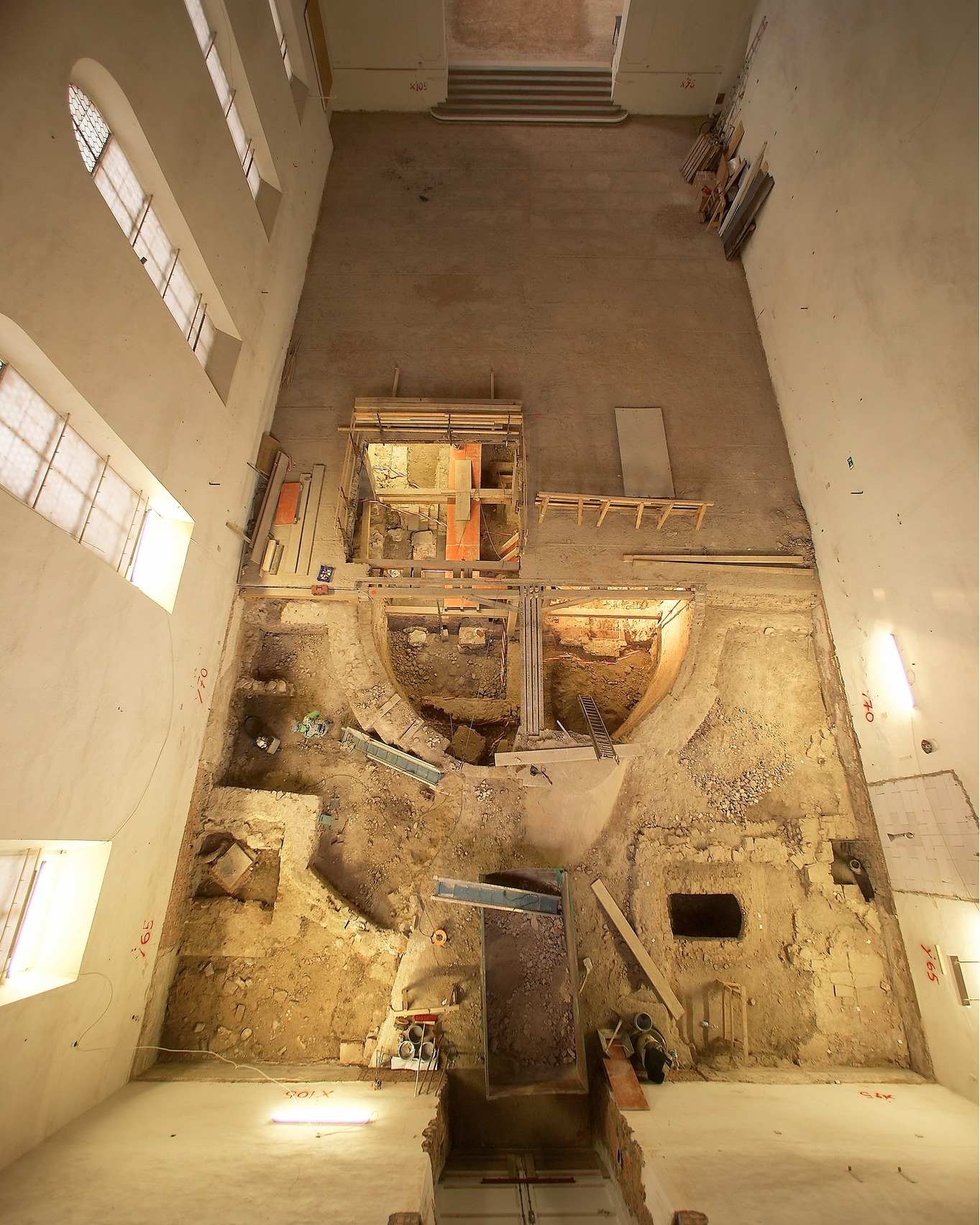 Dieser Alternativtext wurde KI-generiert: Eine Aufnahme von einem Innenraum mit sichtbaren Bauarbeiten und einer tiefen Grube im Boden. Der Raum ist hell und weist mehrere Ebenen sowie bauliche Strukturen auf.
