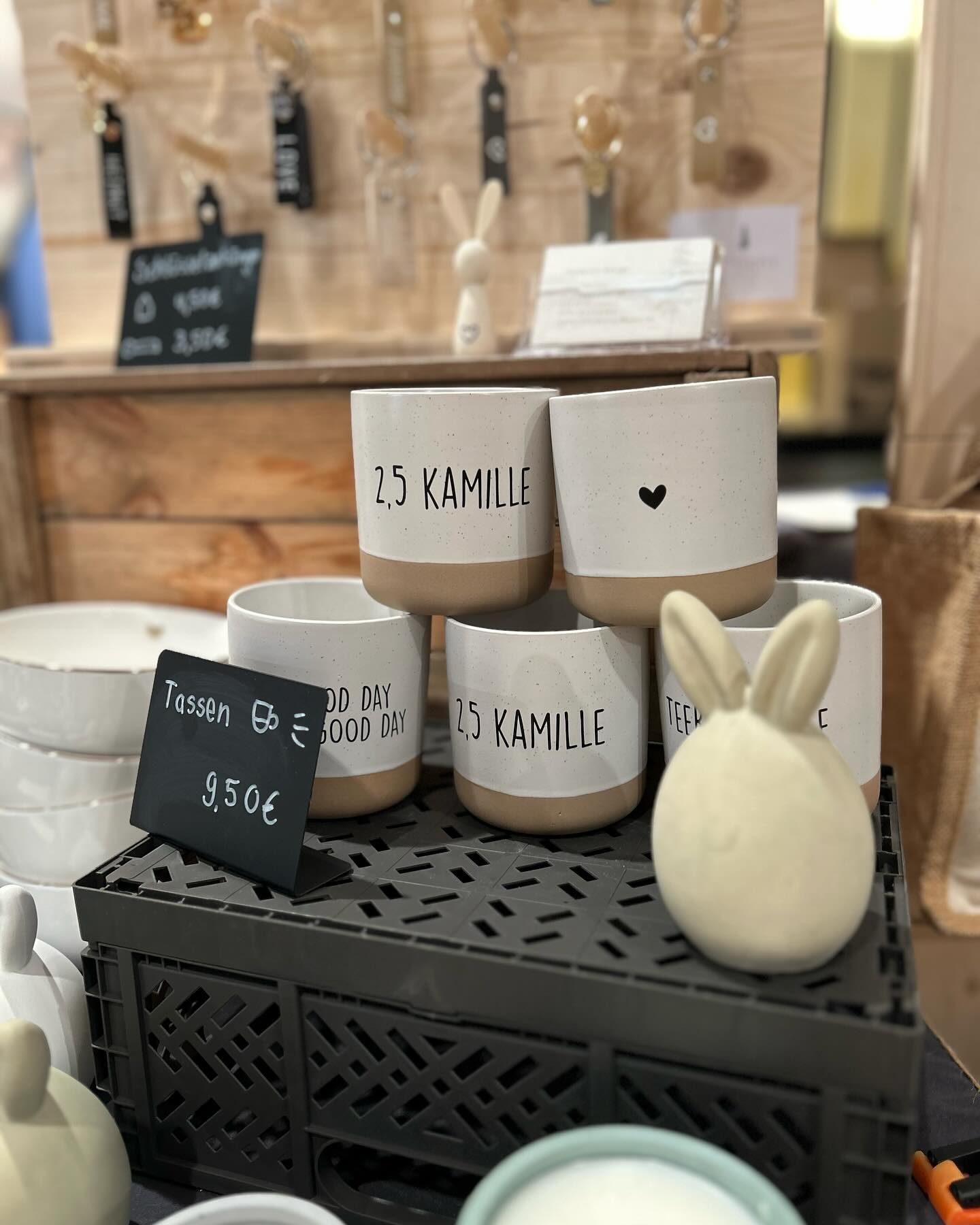 Mehrere Tassen und Dekoartikel stehen auf einem Tisch. Es gibt auch ein Preisschild für die Tassen.