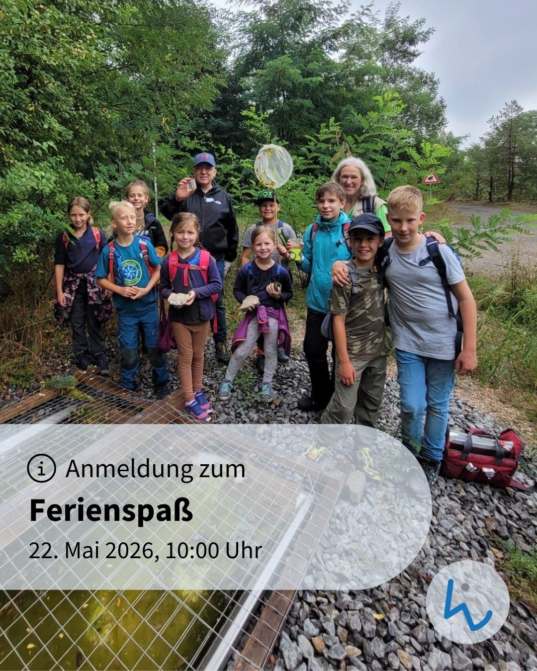 Gruppe von Kindern und Erwachsenen im Freien, ausgestattet mit Rucksäcken und Naturerkundungswerkzeugen, posiert vor einem Waldweg. Überlagert ist ein Textfeld mit der Anmeldung zum Ferienspaß am 22. Mai 2026, 10:00 Uhr. (KI-Alternativtext)