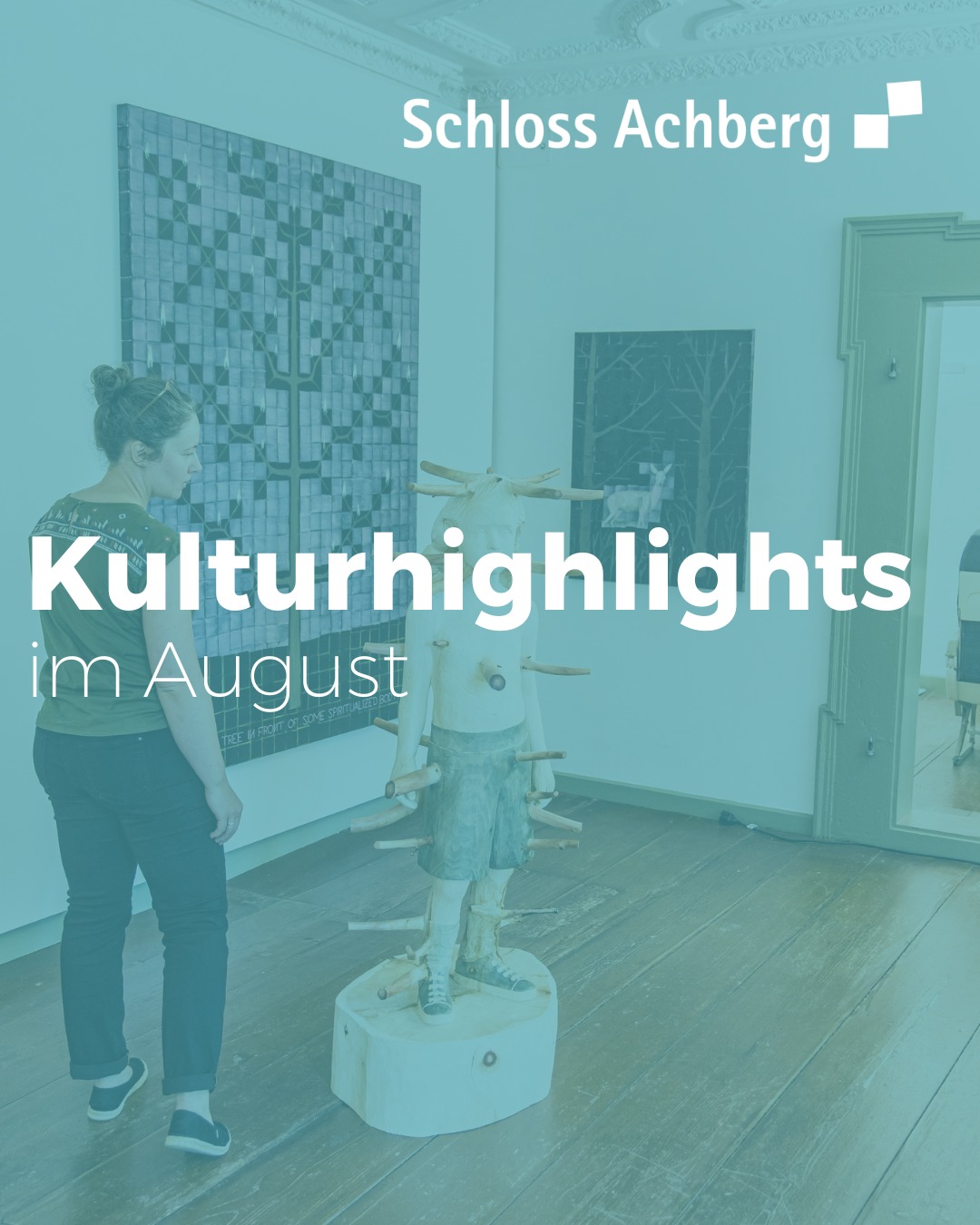 Eine Person betrachtet in einem Raum eine Holzstatue mit Holzstücken, die wie Stacheln herausragen. An der Wand hängen Kunstwerke.
