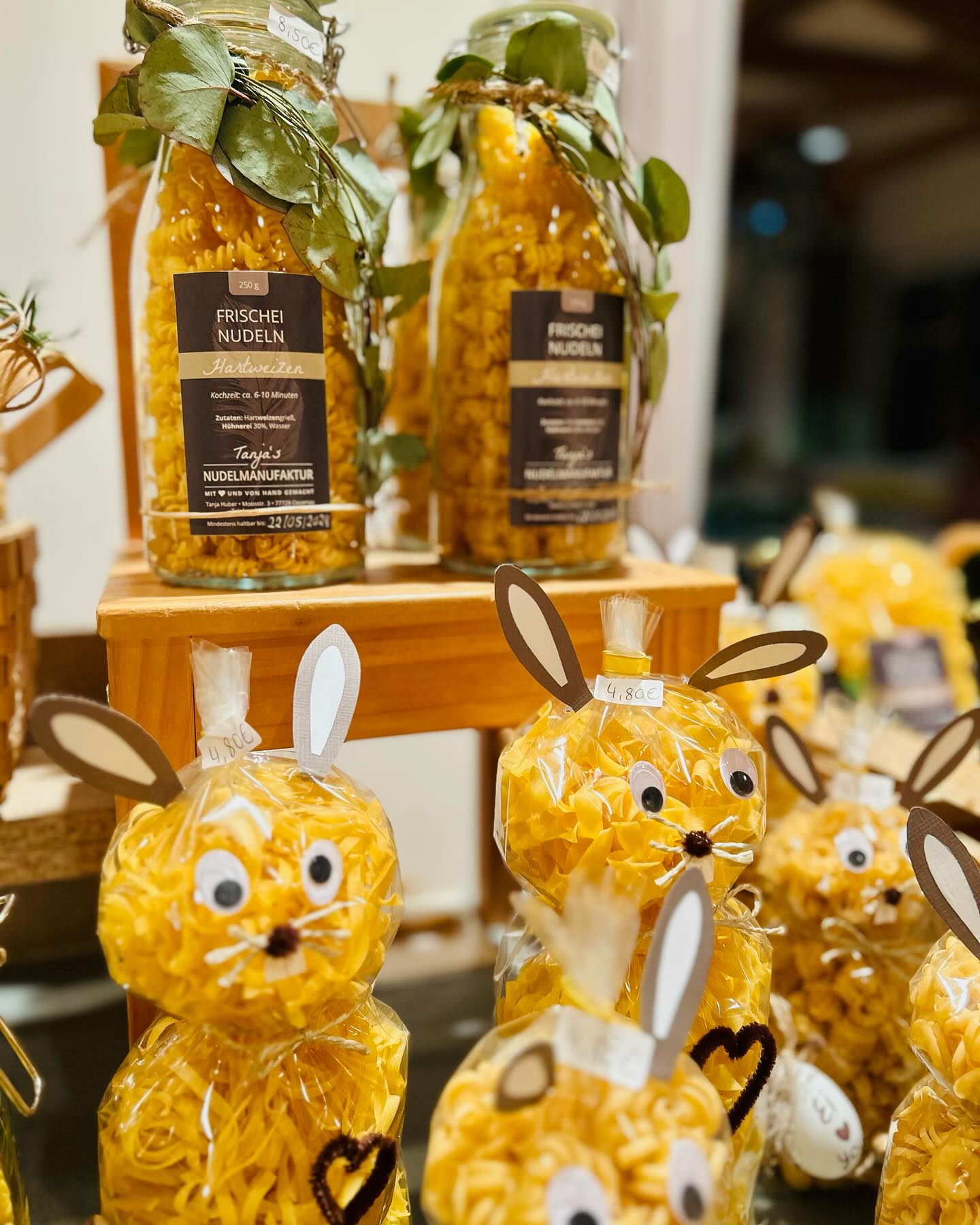 Auf einem Tisch sind Nudelprodukte ausgestellt. Einige sind in durchsichtigen Behältern und andere sehen wie Hasen aus.
