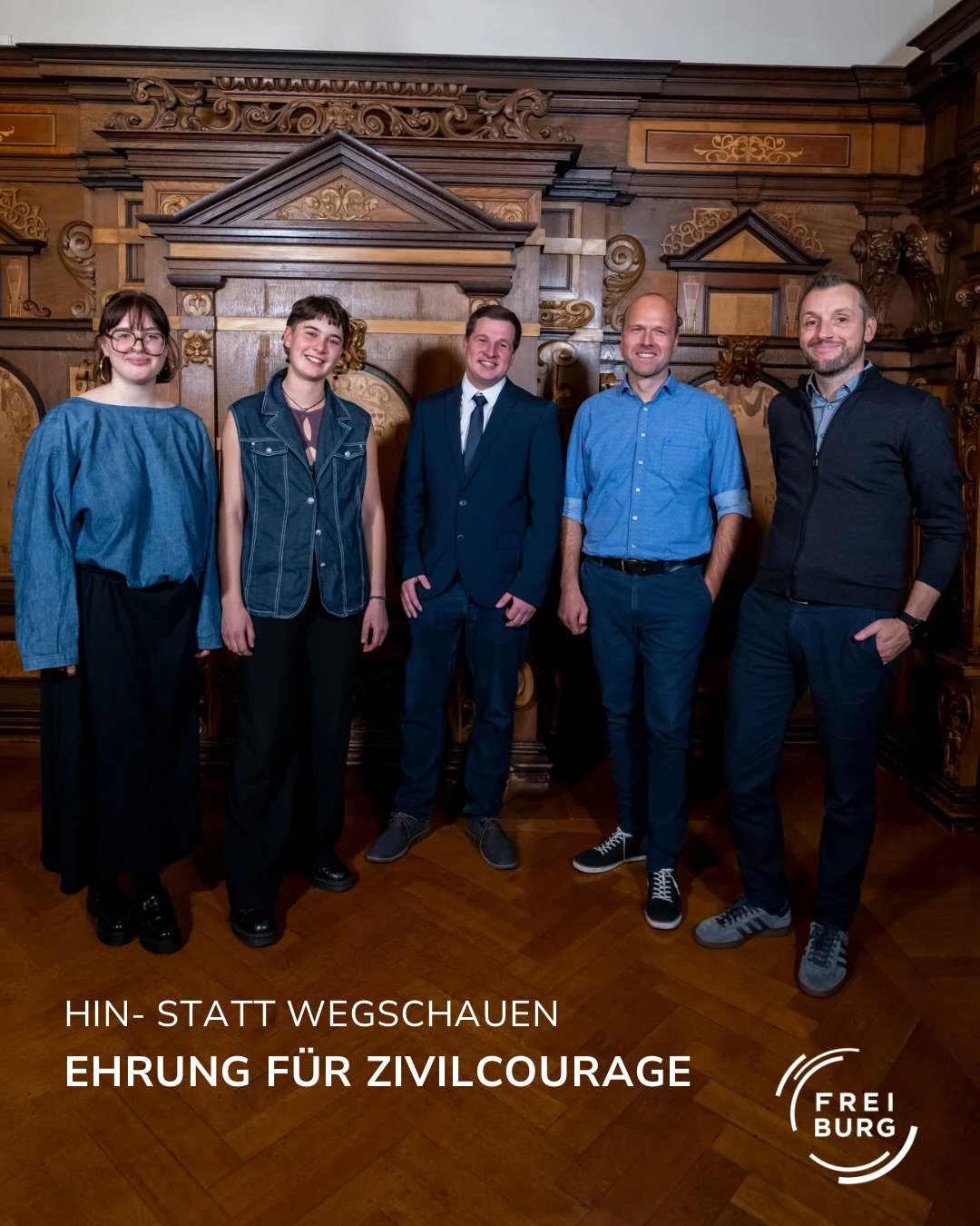 Dieser Alternativtext wurde KI-generiert: Eine Gruppe von fünf Personen steht vor einem reich verzierten Holzpaneel. Unterhalb des Bildes befindet sich ein Text und ein Logo.