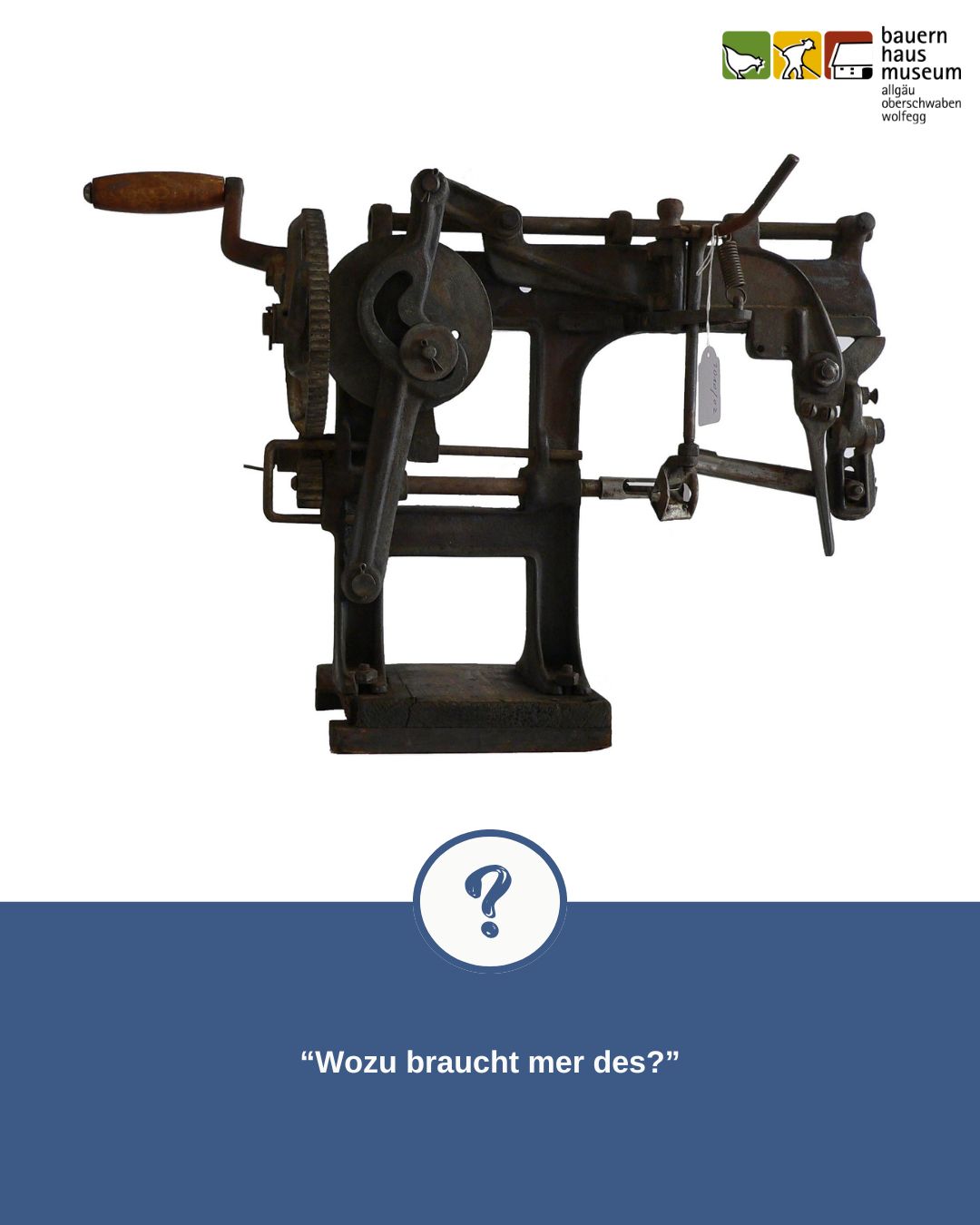 Dieser Alternativtext wurde KI-generiert: Ein altes, metallenes Gerät steht auf einem hellen Untergrund. Unter dem Gerät befindet sich ein blaues Feld mit einem Fragezeichen und einem Text.