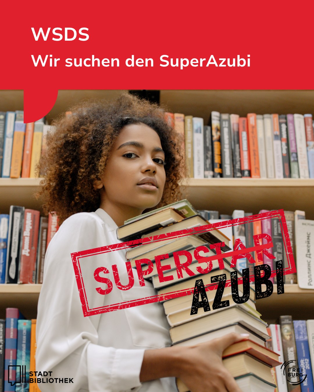 Eine Person mit lockigem Haar hält einen Stapel Bücher vor einem Bücherregal. Über dem Bild steht „WSDS Wir suchen den SuperAzubi“, darüber ein roter Stempel mit „SUPERSTAR AZUBI“. Unten links das Logo der Stadtbibliothek Freiburg. (KI-Alternativtext)