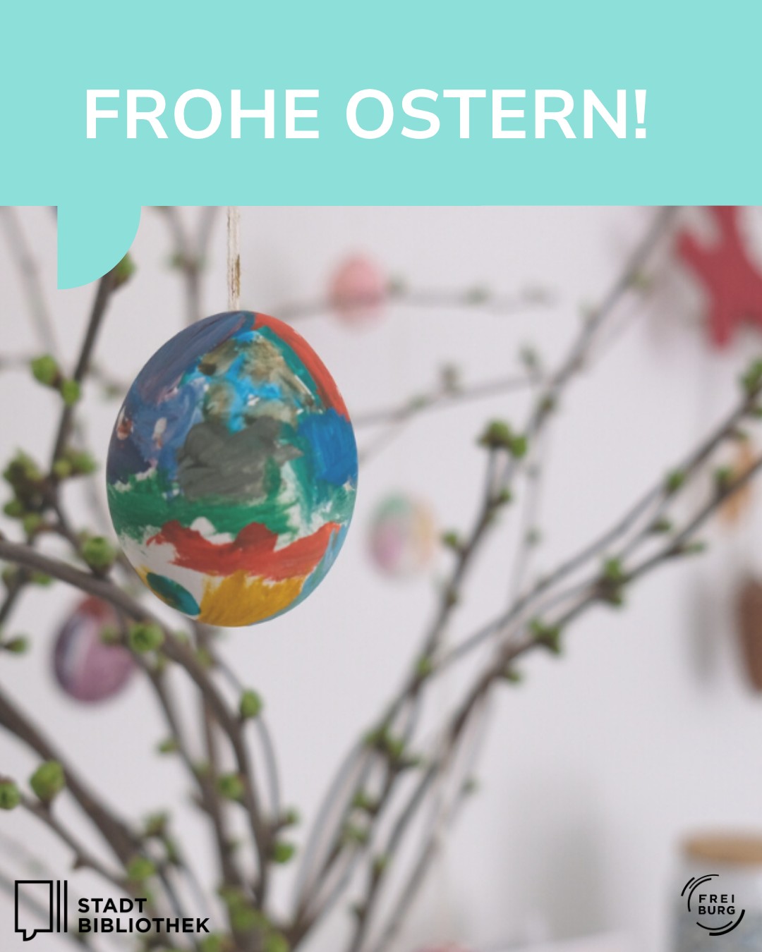 Dieser Alternativtext wurde KI-generiert: Ein verzierter, bemalter Osterei hängt vor einem unscharfen Hintergrund aus Ästen und einer verschwommenen Bibliothek. Das Bild ist farbig und trägt eine saisonale Botschaft.