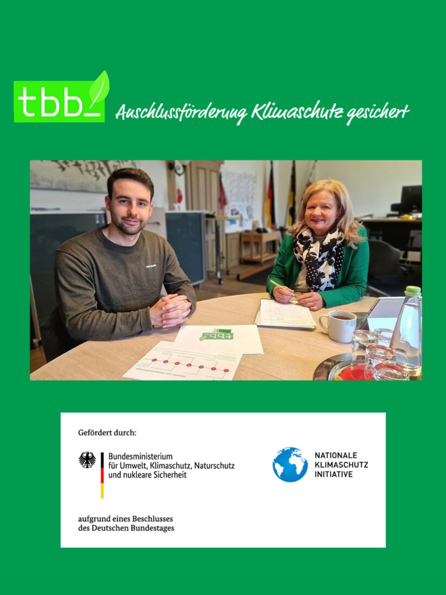 Dieser Alternativtext wurde KI-generiert: Ein farbiges Bild zeigt zwei Personen, die an einem Tisch sitzen und in Dokumente schauen. Im Hintergrund befinden sich weitere Gegenstände und eine Tür.