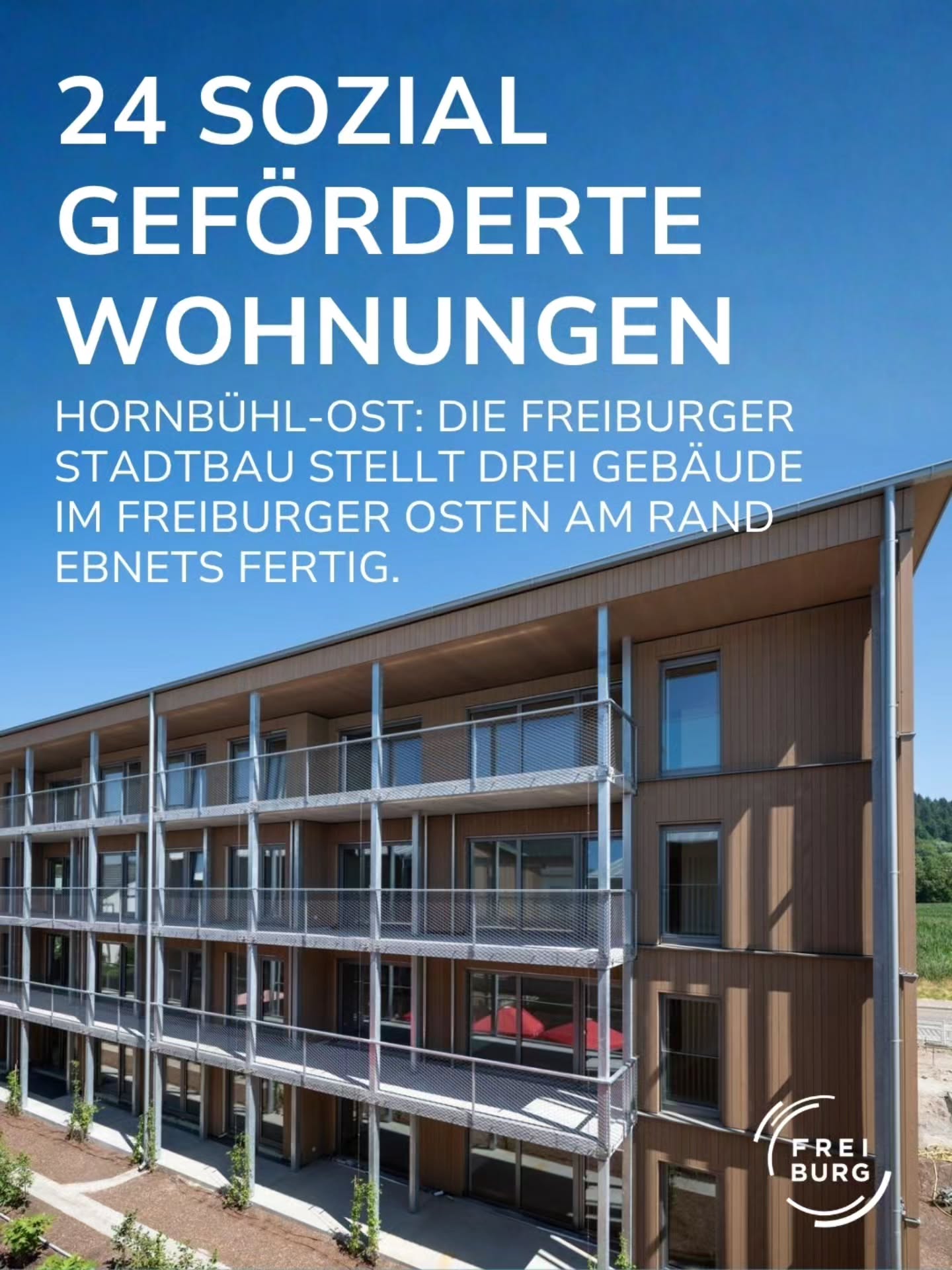 Ein modernes Mehrfamilienhaus mit brauner Holzfassade und Balkonen steht unter blauem Himmel. Oben steht in großen weißen Lettern „24 SOZIAL GEFÖRDERTE WOHNUNGEN“ gefolgt vom Text „HORNBÜHL-OST: DIE FREIBURGER STADTBAU STELLT DREI GEBÄUDE IM FREIBURGER OSTEN AM RAND EBNETS FERTIG.“ Unten rechts ist das Logo „FREIBURG“ platziert. (KI-Alternativtext)