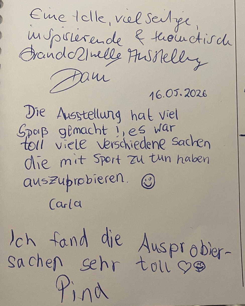 Handgeschriebene Notizen auf einem Blatt Papier: Lob für eine Ausstellung mit vielen sportlichen Aktivitäten, unterzeichnet von Dau (16.05.2028), Carla und Pina, jeweils mit Smiley oder Herz. (KI-Alternativtext)
