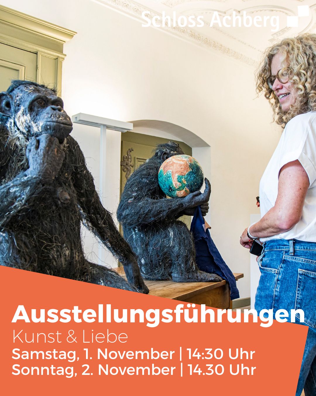 Dieser Alternativtext wurde KI-generiert: Eine Person steht neben zwei Skulpturen in einem Innenraum. Im Hintergrund ist eine Wand mit Dekorationen und Text zu sehen.