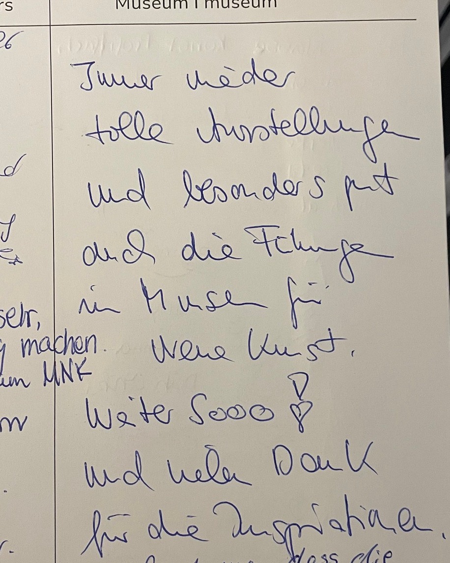 Handgeschriebene Notiz in blauer Tinte auf weißem Papier: „Immer wieder tolle Ausstellungen und besonders gut auch die Führungen im Museum für Neue Kunst. Weiter sooo! und vielen Dank für die Ausnahmen.“ (KI-Alternativtext)
