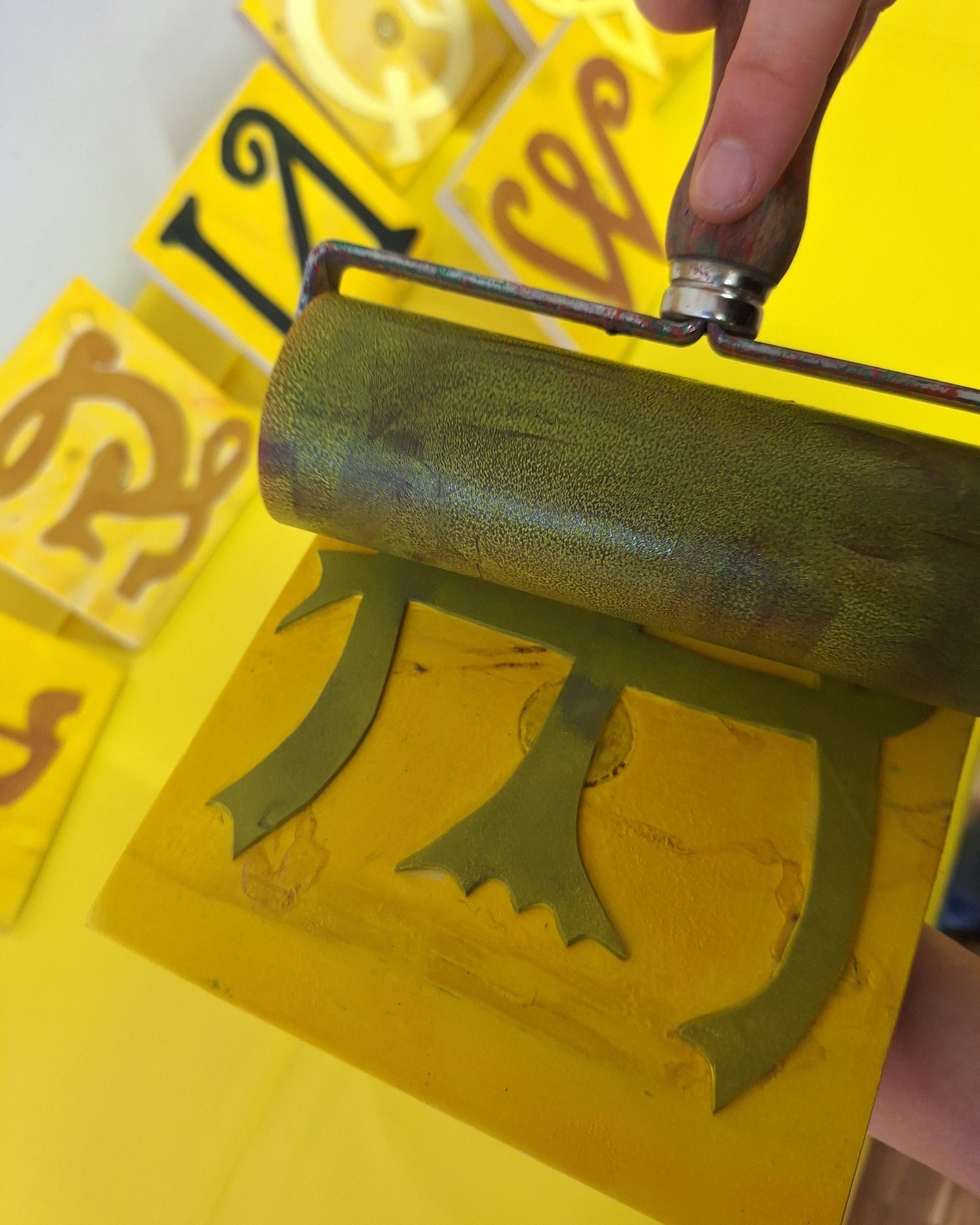 Dieser Alternativtext wurde KI-generiert: Ein Werkzeug wird auf einer gelben Fläche mit einem Muster genutzt. Im Hintergrund sind weitere gelbe Elemente mit ähnlichen Mustern zu sehen.