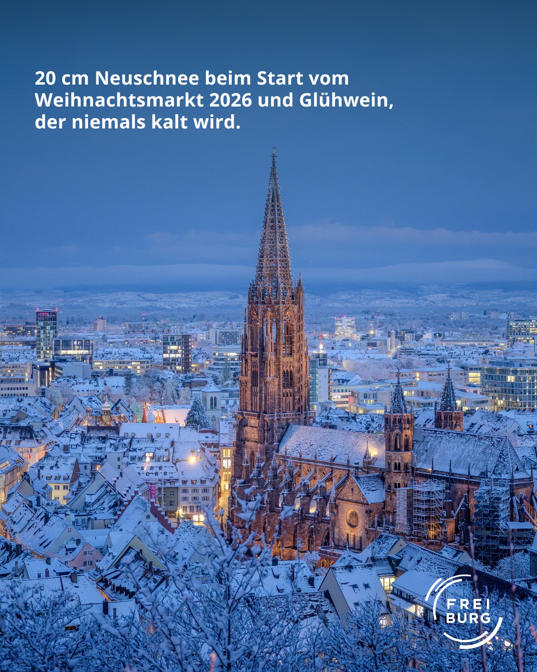 Dieser Alternativtext wurde KI-generiert: Eine verschneite Stadtansicht mit einer hohen, spitzen Kirche im Zentrum. Im Hintergrund erstreckt sich eine beleuchtete Stadtlandschaft unter einem dunklen Himmel.