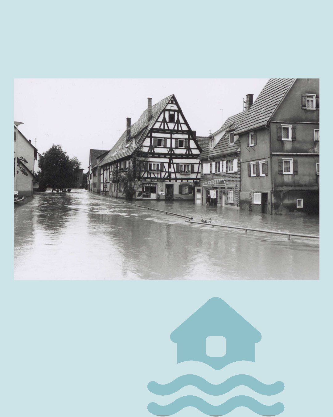Schwarz-Weiß-Fotografie einer überfluteten Dorfstraße mit Fachwerkhäusern und einem Haus mit der Aufschrift A.P.S. im Erdgeschoss. Im Vordergrund befindet sich ein modernes blaues Symbol eines Hauses, das von drei Wellenlinien umgeben ist. (KI-Alternativtext)