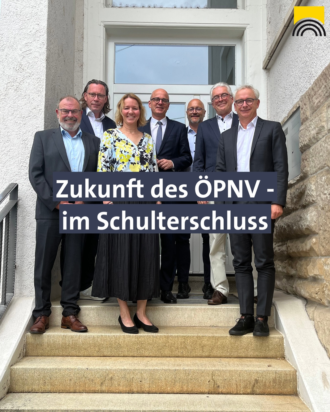 Eine Gruppe von sieben Personen steht draussen auf einer Treppe. Ein Textoverlay mit "Zukunft des ÖPNV - im Schulterschluss" ist auch zu sehen.