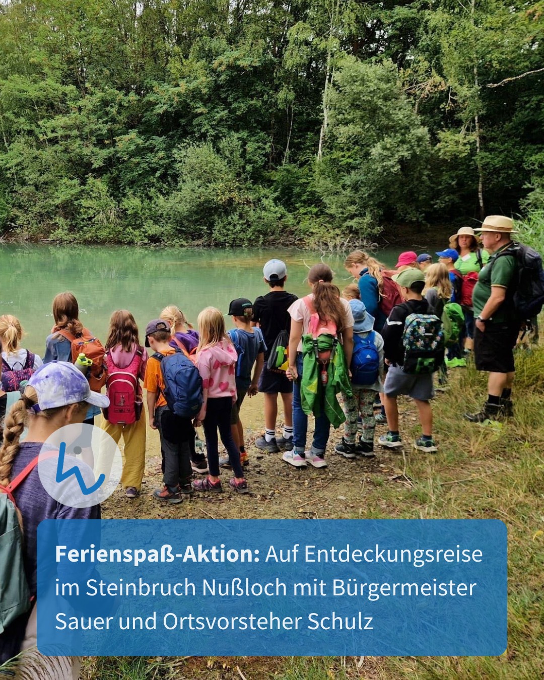Eine Gruppe von Kindern mit Rucksäcken und einige Erwachsene stehen am Ufer eines Gewässers vor einem Wald. Ein Erwachsener rechts trägt eine Kopfbedeckung und einen Rucksack. Ein blauer Textbanner unten lautet: "Ferienspaß-Aktion: Auf Entdeckungsreise im Steinbruch Nußloch mit Bürgermeister Sauer und Ortsvorsteher Schulz". (KI-Alternativtext)