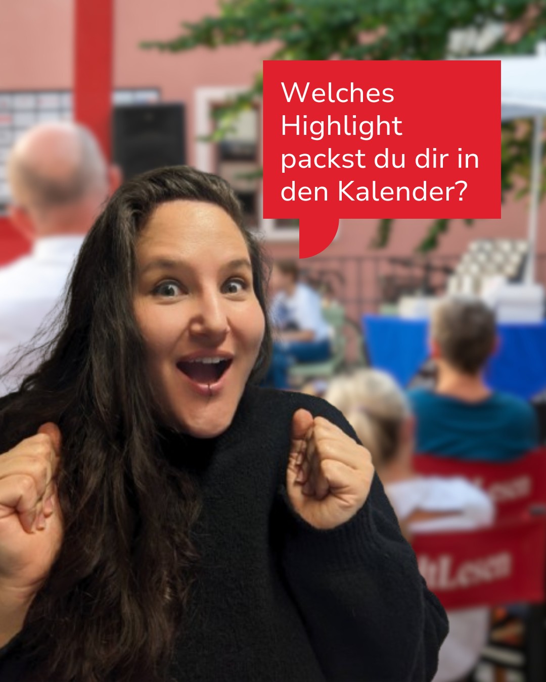 Eine Person mit langen dunklen Haaren und schwarzer Strickjacke zeigt mit beiden Fäusten nach oben und lächelt begeistert. Ein roter Sprechblasentext fragt: „Welches Highlight packst du dir in den Kalender?“ Im Hintergrund sind unscharf weitere Personen und ein roter Tisch zu sehen. (KI-Alternativtext)