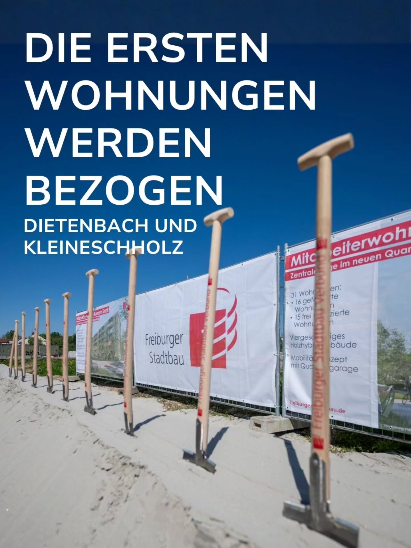 Großer weißer Text auf blauem Himmel lautet: "DIE ERSTEN WOHNUNGEN WERDEN BEZOGEN DIETENBACH UND KLEINESCHHOLZ". Im Vordergrund stehen mehrere Schaufeln mit Holzgriffen im Sand. Dahinter verläuft ein weißer Bauzaun mit dem Logo von Freiburger Stadtbau und Informationen zu Mitarbeiterwohnungen. (KI-Alternativtext)