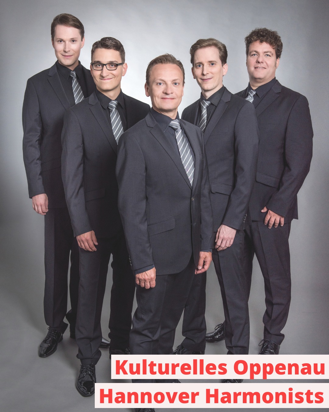 Dieser Alternativtext wurde KI-generiert: Eine Gruppe von Personen in dunklen Anzügen steht für ein Porträt zusammen. Im unteren Bildbereich befindet sich ein roter Schriftzug.