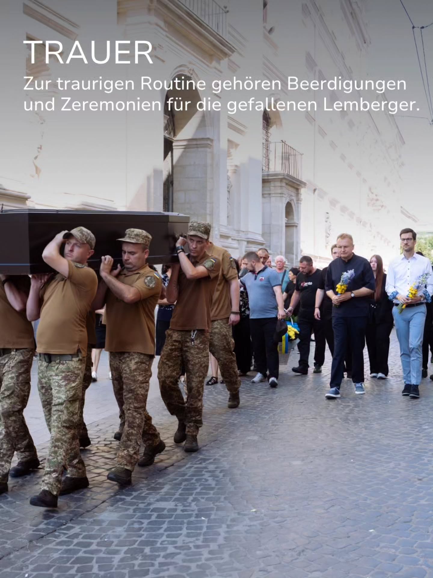 Personen in Uniform tragen einen schwarzen Sarg auf einer gepflasterten Straße, gefolgt von weiteren Personen, die Blumen halten. Oben im Bild steht der Text „TRAUER“ und darunter „Zur traurigen Routine gehören Beerdigungen und Zeremonien für die gefallenen Lemberger.“ (KI-Alternativtext)