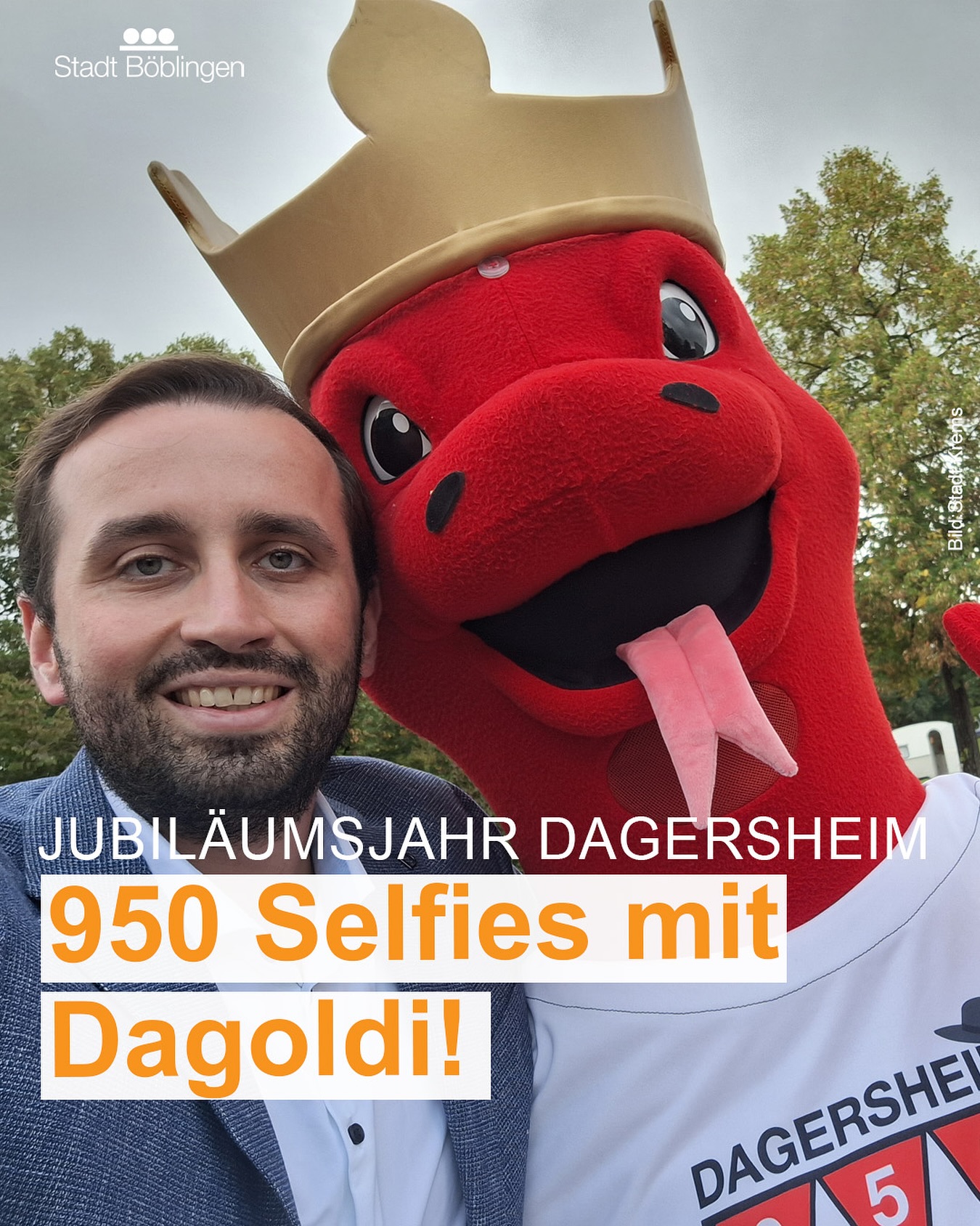 Dieser Alternativtext wurde KI-generiert: Ein farbiges Bild zeigt eine Person neben einer großen, roten Vogel-Figur. Im Vordergrund befindet sich ein Banner mit der Aufschrift "Jubiläumsjahr Dagersheim 950 Selfies mit Dagoldi!". 