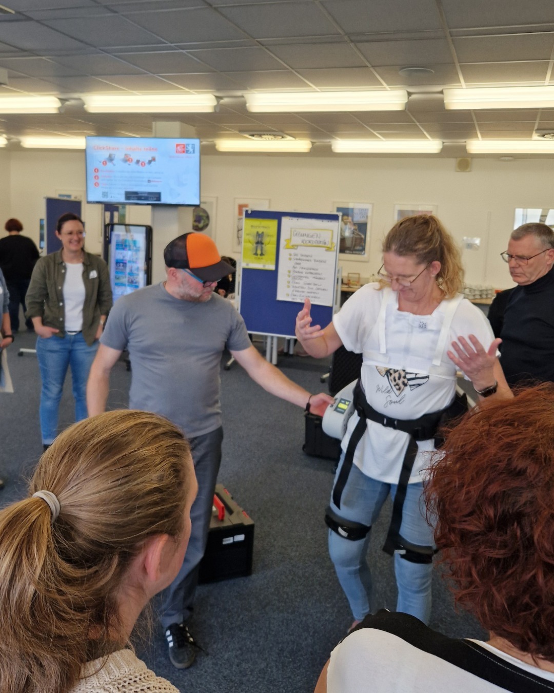 Weibliche Person testet ein "Exosklette". Andere Personen sehen ihr dabei zu.