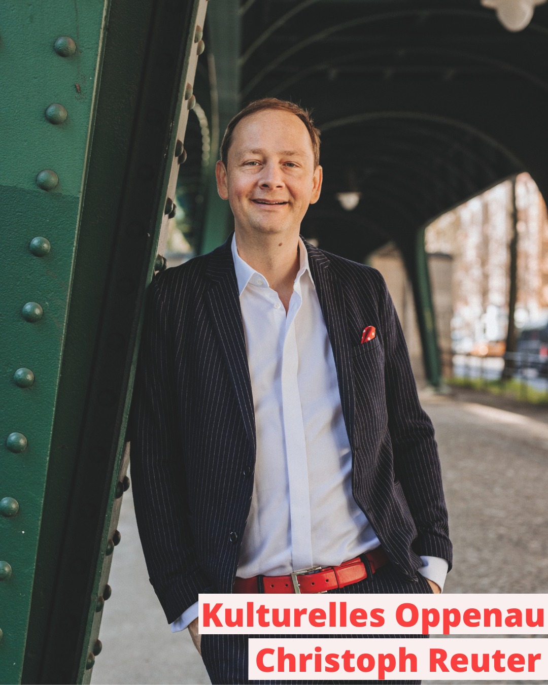 Dieser Alternativtext wurde KI-generiert: Eine Person lehnt lächelnd an einem grünen Stahlträger. Im Hintergrund ist eine Lichtung zu sehen.