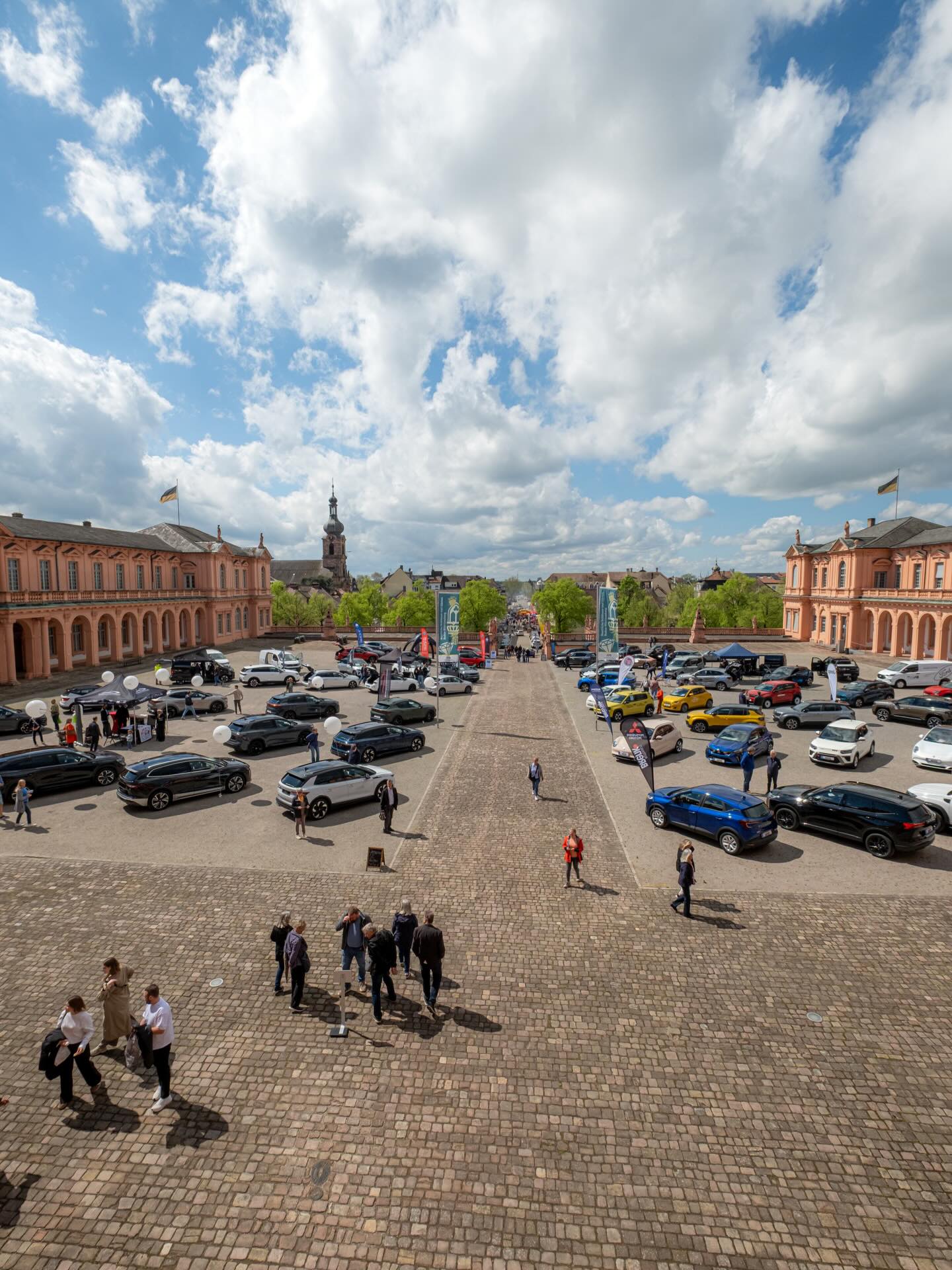 Dieser Alternativtext wurde KI-generiert: Eine weite, gepflasterte Platzfläche wird von Gebäuden mit Kuppeln und einer Flagge eingerahmt. Auf dem Platz und den umliegenden Straßen befinden sich viele Fahrzeuge und wenige Personen.
