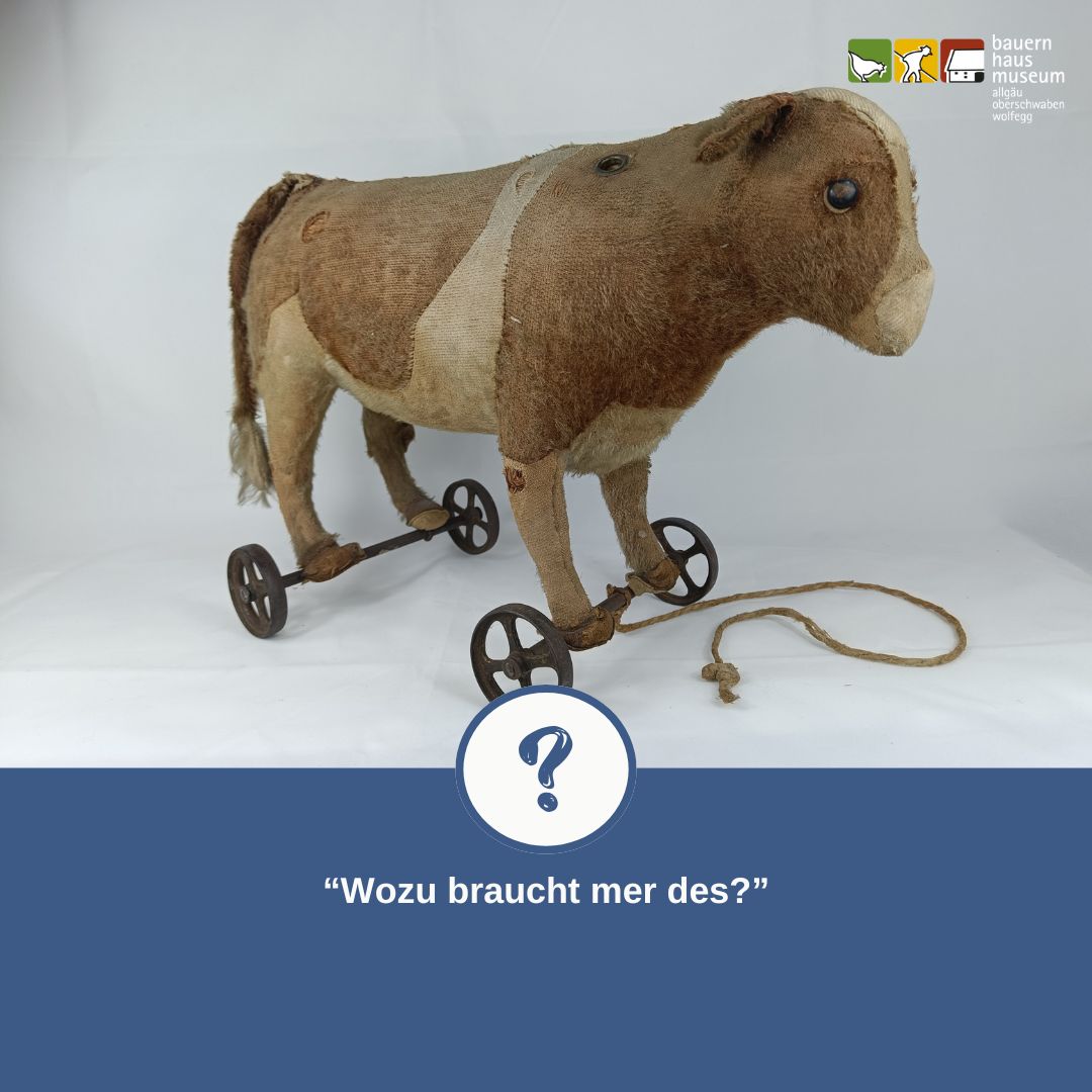 Dieser Alternativtext wurde KI-generiert: Ein altes, braunes Spielzeug auf Rädern steht auf einem hellen Untergrund. Ein Fragezeichen ist im Vordergrund zu sehen.