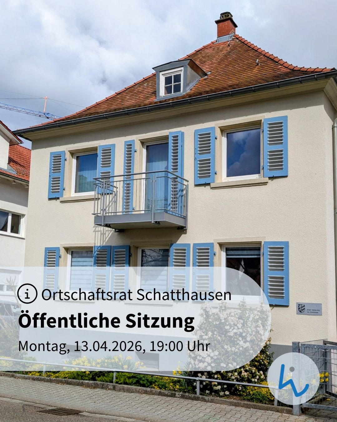 Dieser Alternativtext wurde KI-generiert: Ein mehrstöckiges Gebäude mit blauen Fensterläden und einem Balkon ist zu sehen. Ein Plakat mit Informationen über eine öffentliche Sitzung befindet sich im Vordergrund.